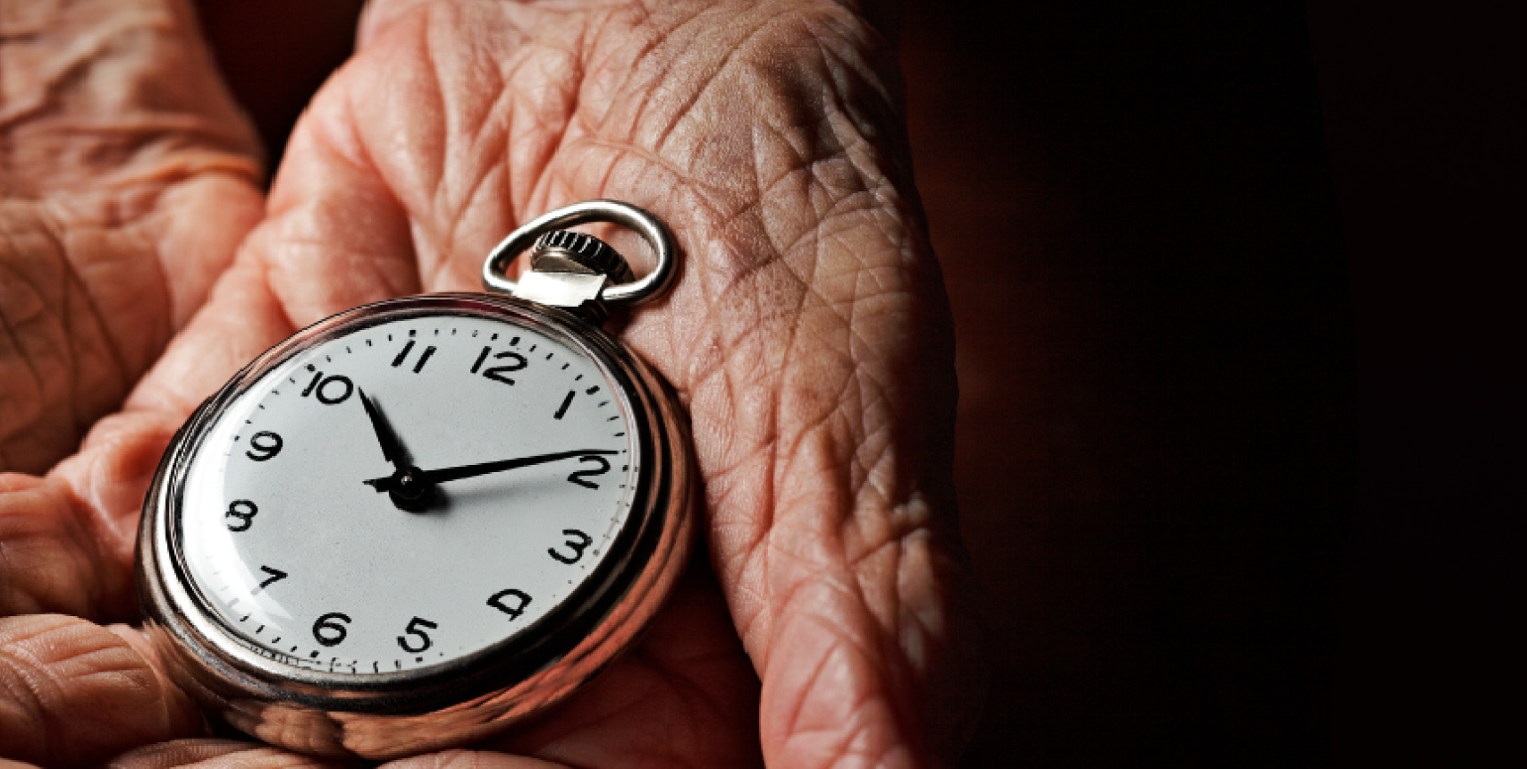 The hands of an aged person holding a pocket watch.